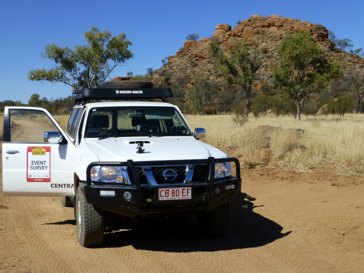 Survey car in front of a rocky outcrop.